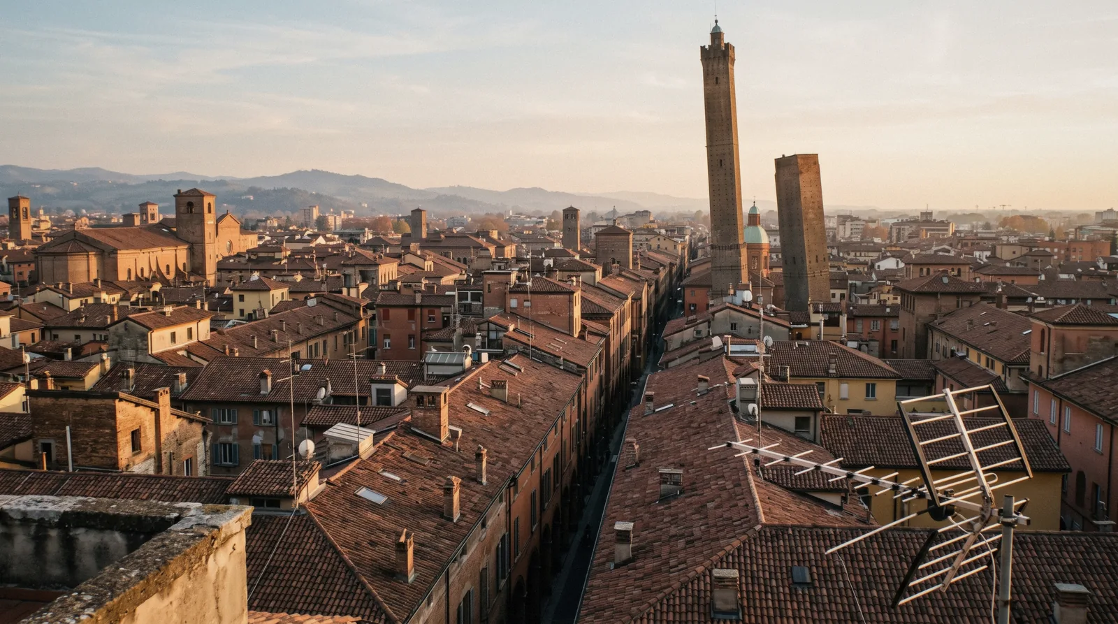 Terracotta rooftops, porticoes and the leaning towers seen at golden hour, the reward of a Bologna day trip from Florence
