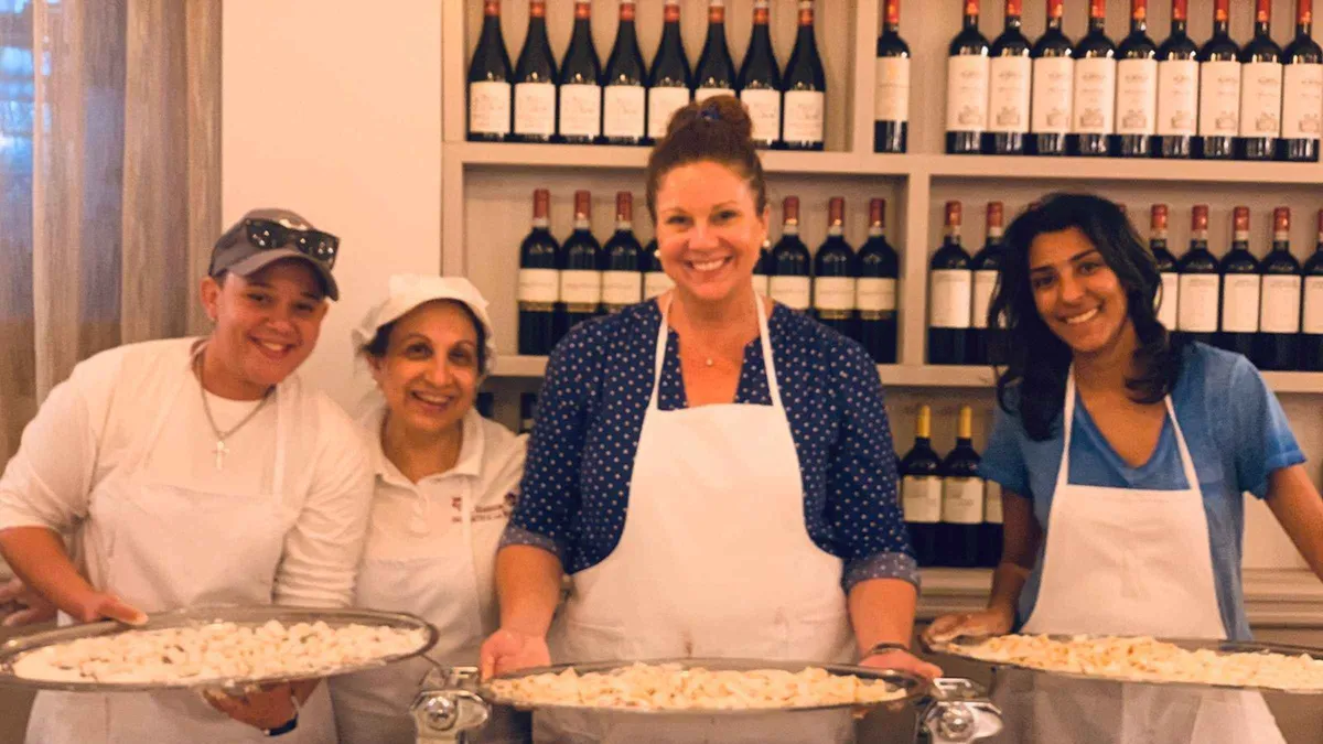Layering tiramisu in a restaurant kitchen on a Florence pasta and tiramisu cooking class in Italy