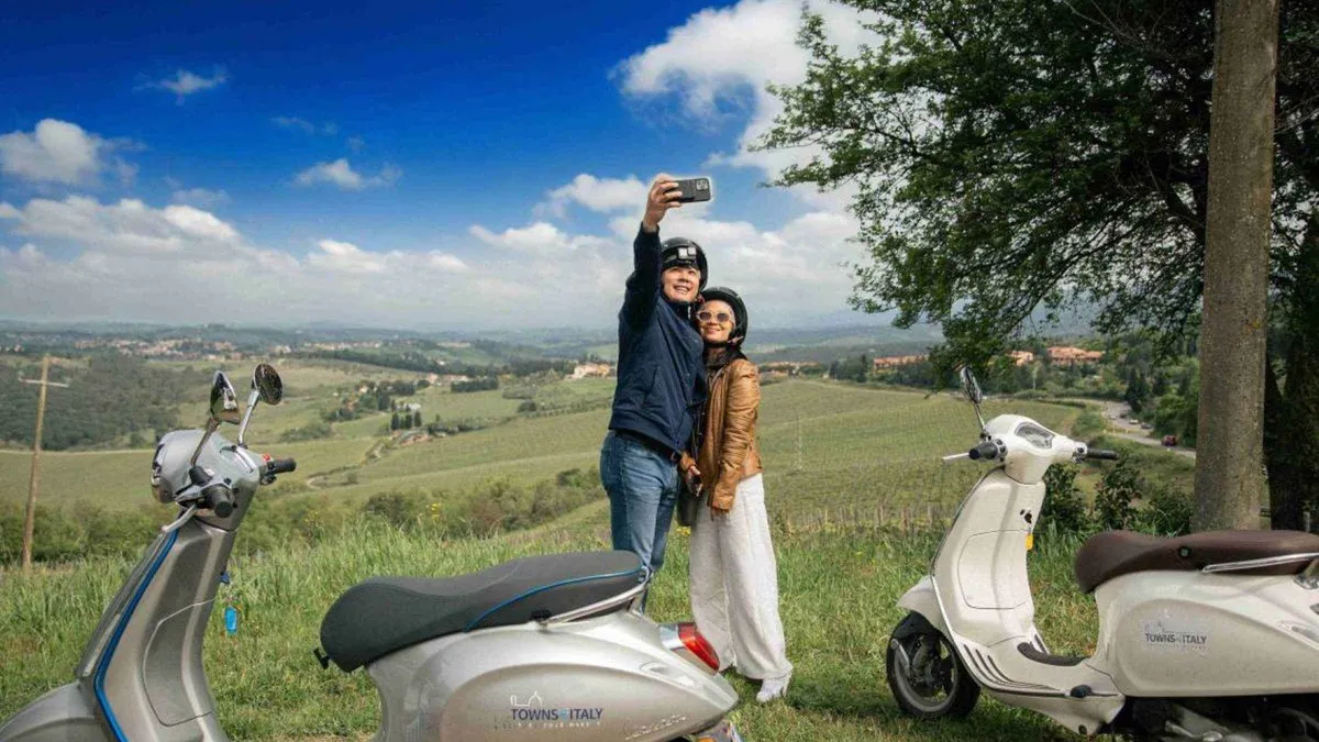 Riders on Vespas between Chianti vineyards on a Vespa tour from Florence, Italy