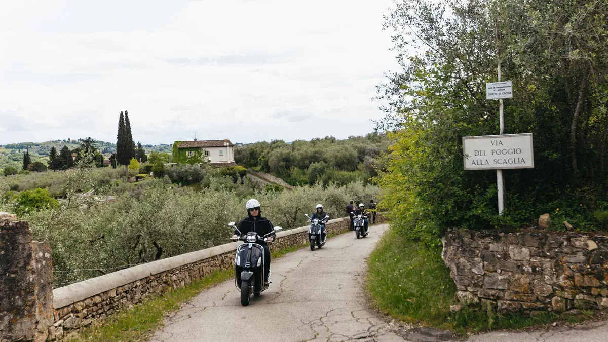 Vintage Vespa parked on a cypress-lined road on a Tuscan countryside Vespa tour from Florence, Italy