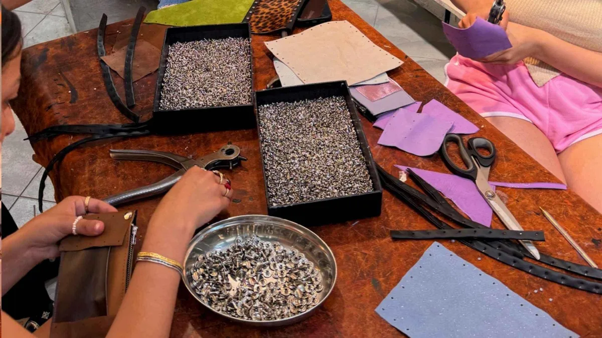 Hand-stitching leather at an artisan bench on a Florence leather wallet workshop in Italy