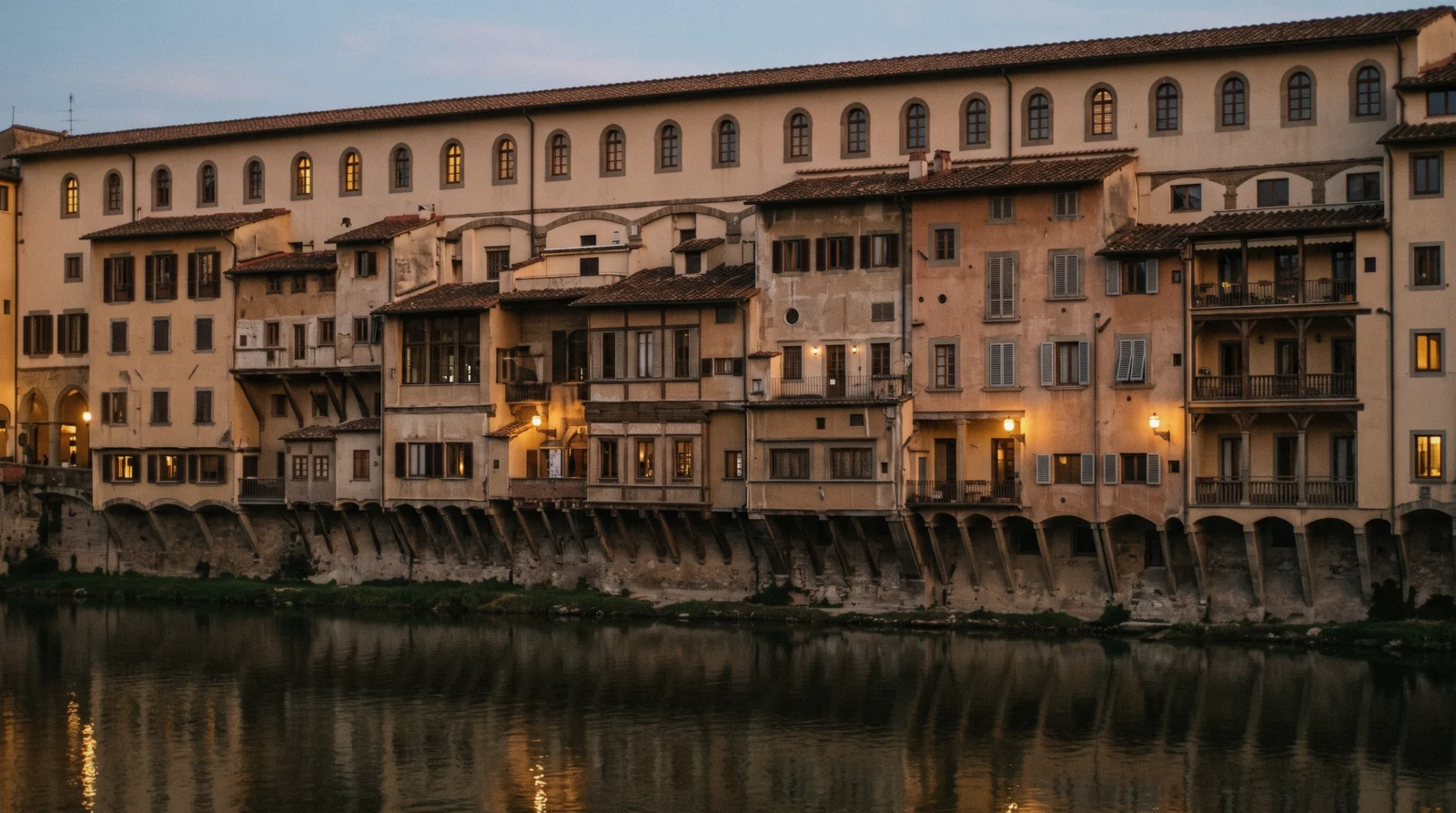 The arched windows of the Vasari Corridor running above the shops of the old bridge, seen from the Arno embankment in evening light, Vasari Corridor Florence