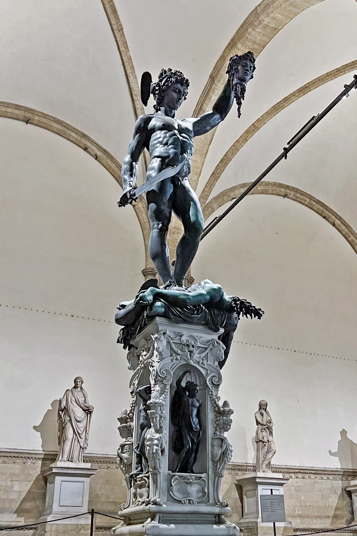 Cellini's bronze Perseus holding up the head of Medusa under the arches of the Loggia dei Lanzi, Piazza della Signoria, Florence